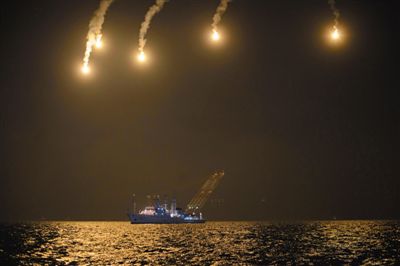 22日，搜救人員在照明彈的光亮下連夜搜救。