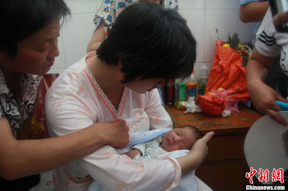 圖為久別重逢，獲救嬰兒母親悉心撫摸愛子。張一辰 攝