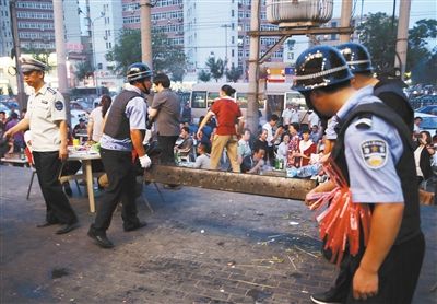 6月13日晚8點(diǎn)，朝陽(yáng)路和青年路交叉口西側(cè)，一次聯(lián)合執(zhí)法行動(dòng)中，輔警與協(xié)管抬走商戶的燒烤用具。新京報(bào)記者 尹亞飛 攝