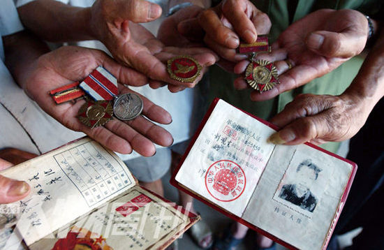 幾位志愿軍老兵展示自己的立功證、傷殘軍人證與勛章