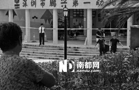→7月19日，鵬興花園第一幼兒園門前，民警在現(xiàn)場進(jìn)行完勘查取證后，園長和保安的尸體被運(yùn)走。南都記者 徐文閣 攝