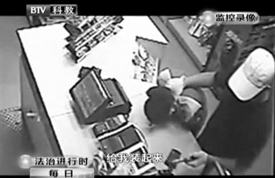 戴帽男子一手掐住加油站營業(yè)員，一手持發(fā)令槍指向另一營業(yè)員，要求“把錢給我裝起來”。