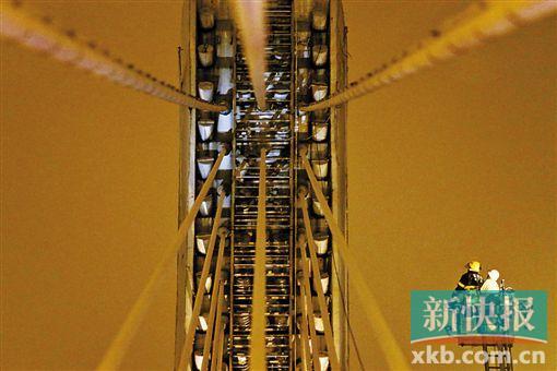 截至今日零時(shí)，男子仍未有下橋舉動(dòng)。圖為公安和消防人員乘消防云梯在高空上和男子交談。