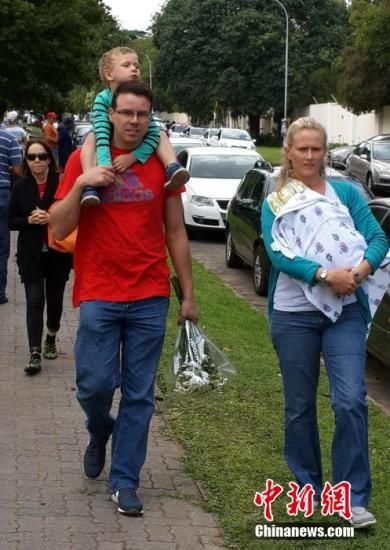 圖為一個(gè)白人家庭，由父母帶著孩子到曼德拉家門(mén)外悼念。中新社發(fā) 宋方燦 攝
