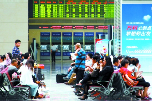 候車大廳溫度很高，一名乘客一手扇風(fēng)、一手擦汗