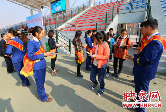 活動現(xiàn)場工作人員給同學(xué)們發(fā)放宣傳冊、環(huán)保袋。