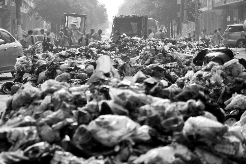 垃圾堆滿整個(gè)路口，環(huán)衛(wèi)工人們正在清理