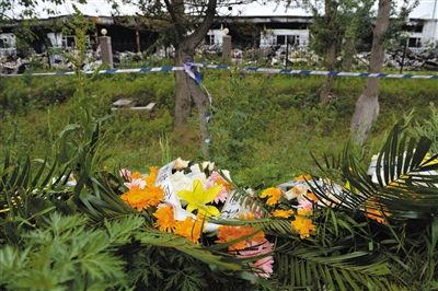 昨日，吉林省德惠市吉林寶源豐禽業(yè)有限公司燃燒事故現(xiàn)場警戒線外，遇難者家屬在路邊擺放了花圈祭奠逝去的親人。吳江 攝