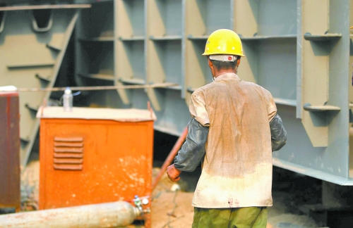 工地上，一建筑工人的衣服被汗水浸透。