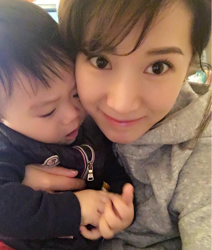 照片中李念狂吻兒子，小寶貝自顧自地玩著。