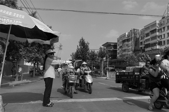 昨日，開(kāi)封市區(qū)一名協(xié)管員在指揮群眾過(guò)馬路