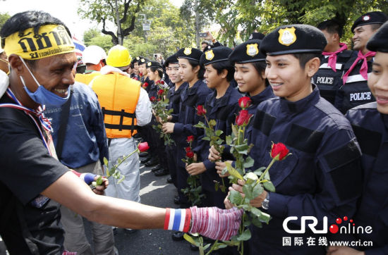 2013年12月03日,曼谷總理府與曼谷警署允許反政府示威民眾進(jìn)入,雙方進(jìn)入暫時“停戰(zhàn)”狀態(tài)迎接泰王生日。曼谷警察總署,女警們手持鮮花送給反政府示威民眾。圖片來源:Manish Swarup/東方IC