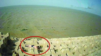 孫正龍游上岸，趴在海邊精疲力盡。