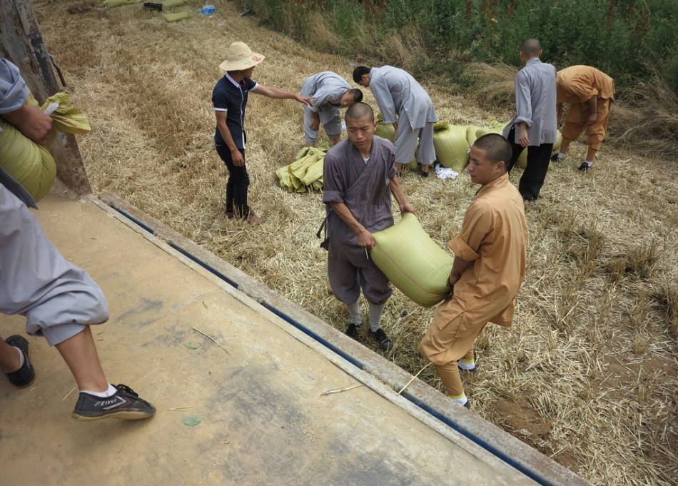 武僧將打包后的糧食集中至運輸車輛上。