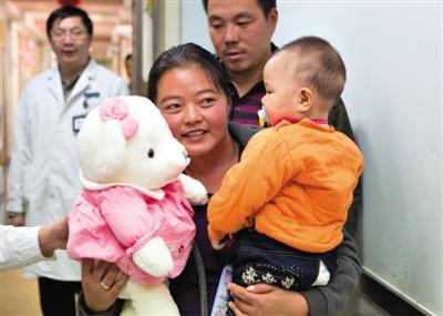 昨日上午，被扎針女嬰的母親抱著孩子和醫(yī)護人員送的玩偶準備出院，院方稱孩子術(shù)后恢復(fù)良好。記者 高瑋 攝